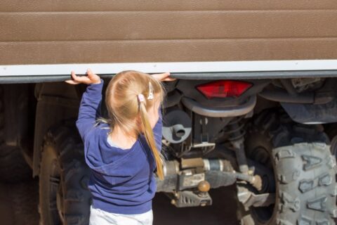 Child lifting a garage door, illustrating important garage door safety features in Chicago, IL