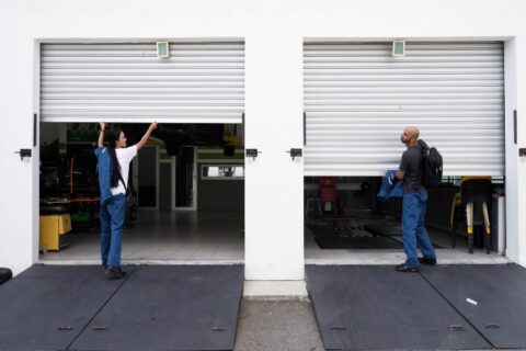 Two workers are lifting garage doors as part of noise reduction testing in Chicago, IL