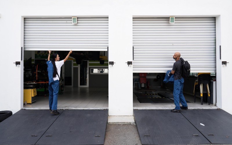 Two workers are lifting garage doors as part of noise reduction testing in Chicago, IL
