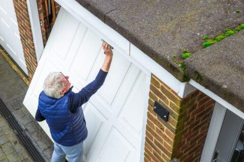 An old man is painting the garage door in Chicago, IL