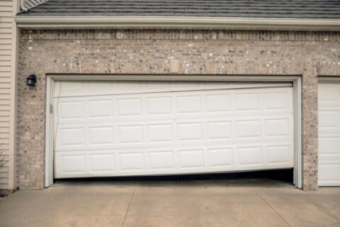 Damaged garage door hanging unevenly after failed repair requiring replacement